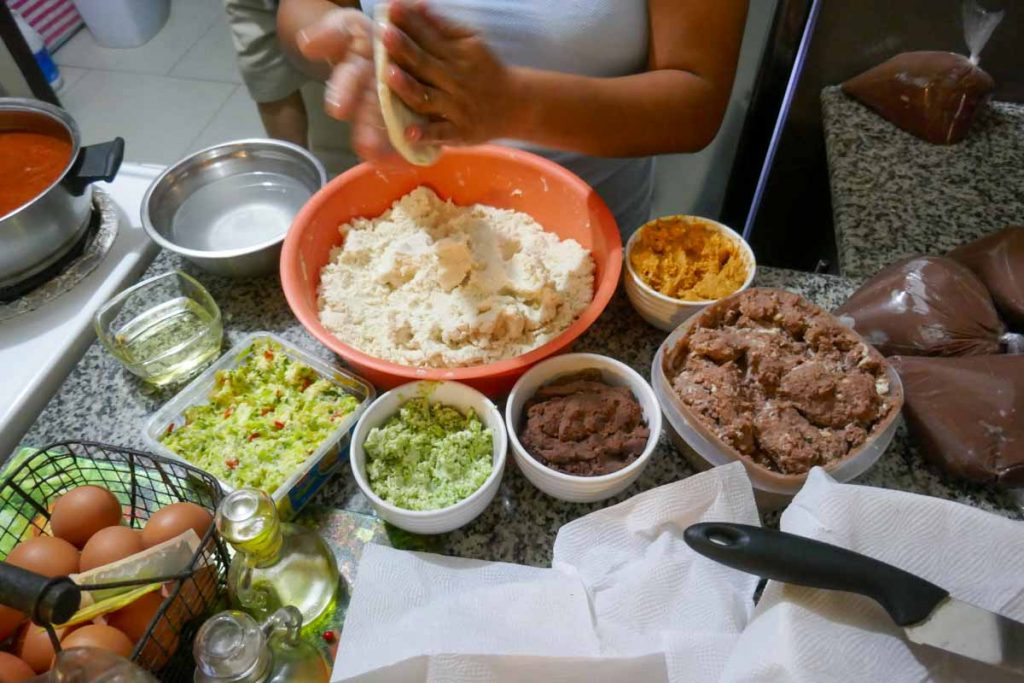 Turn and pat the filled pupusa dough ball to flatten it.