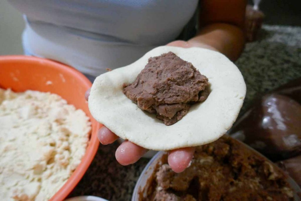 Pupusa filing in the middle of a circle of dough.