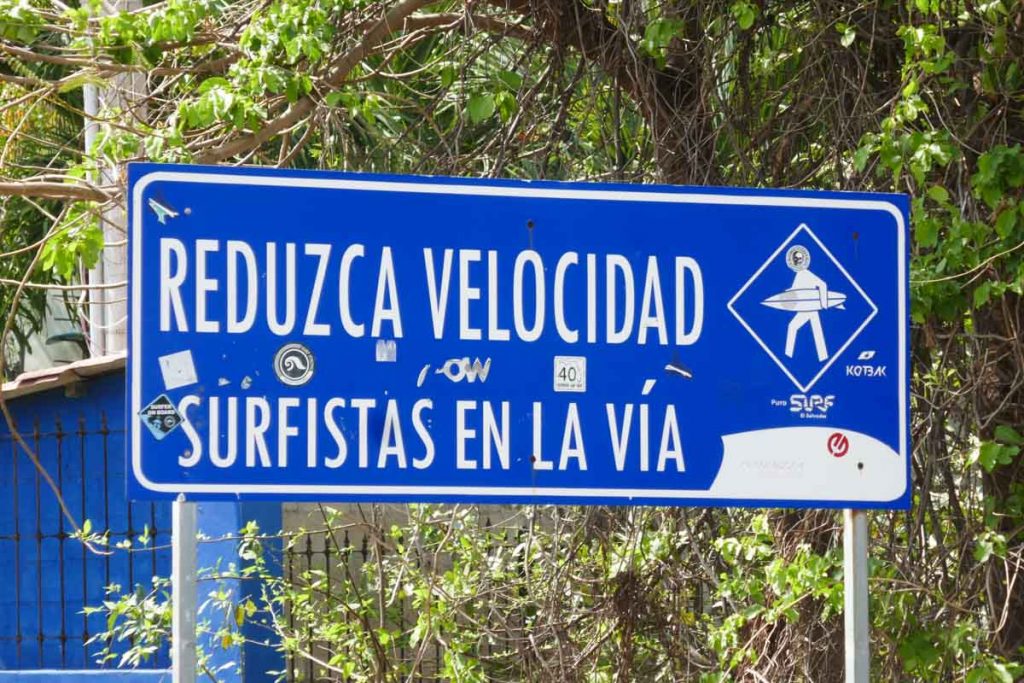 Surfing in El Salvador. Sign post warns motorists to beware of surfers in the street.