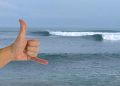Surfing El Salvador wave El Sunzal. Shaka hand signal infront of breaking waves.