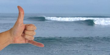 Surfing El Salvador wave El Sunzal. Shaka hand signal infront of breaking waves.