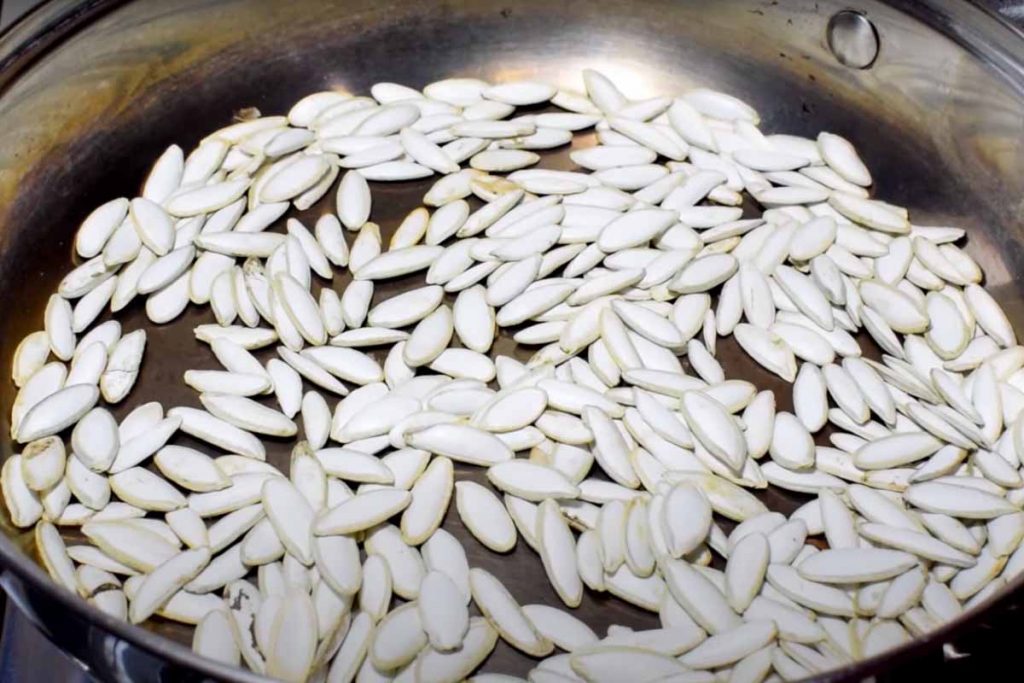 Toasting pumpkin seeds with the husk on in a pan 